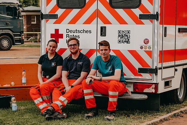 drei HelferInnen sitzen auf einem RTW